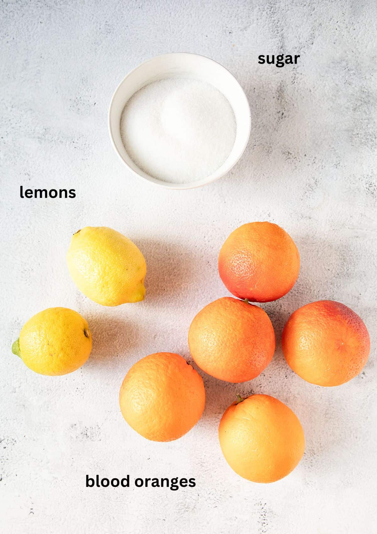 a bowl of sugar, two lemons and five oranges for making jam.