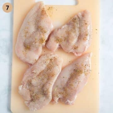 seasoning four chicken breasts before cooking.