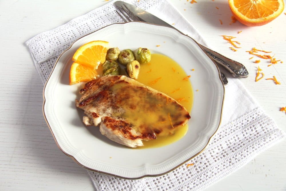 plate with a piece of chicken breast with orange sauce.