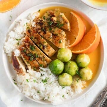 chicken with orange sauce served with rice on a plate.