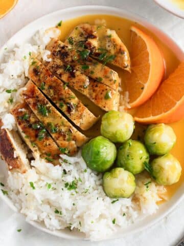 chicken with orange sauce served with rice on a plate.