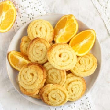 overhead view of a plate of swirl cookies with jam and a few orange wedges.