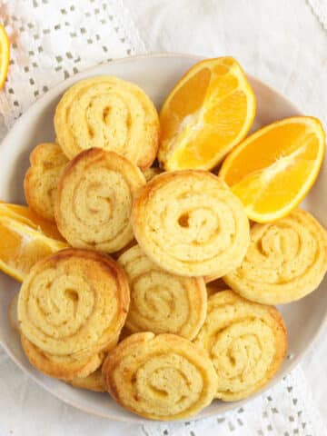 overhead view of a plate of swirl cookies with jam and a few orange wedges.