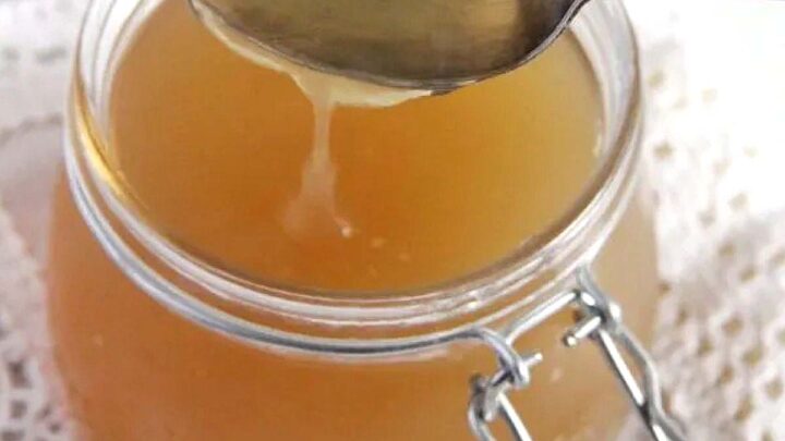turkey bone broth being poured from a tablespoon in a jar.