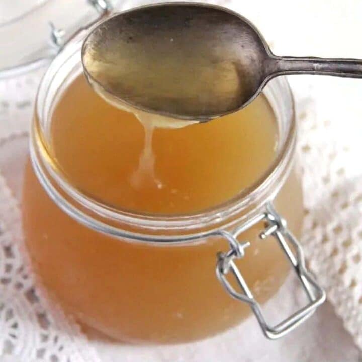 turkey bone broth being poured from a tablespoon in a jar