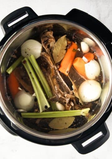 turkey bones and vegetables in an instant pot before being cooked.