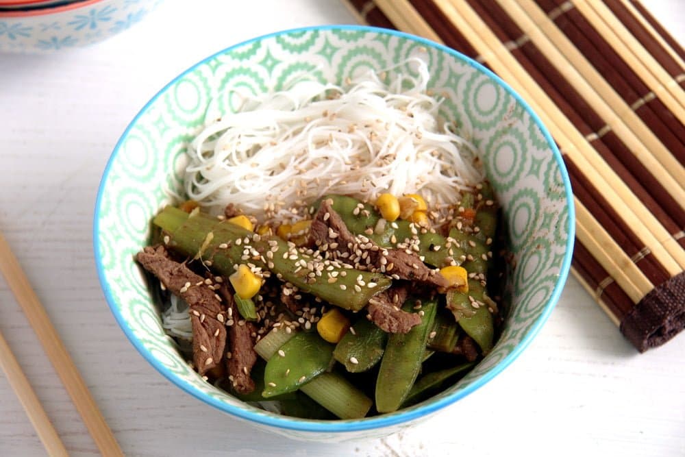 beef, noodles, corn, scallions, sugar snap peas with broth in a bowl