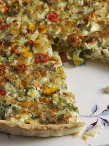 close up of green onion quiche with a piece cut out of it.