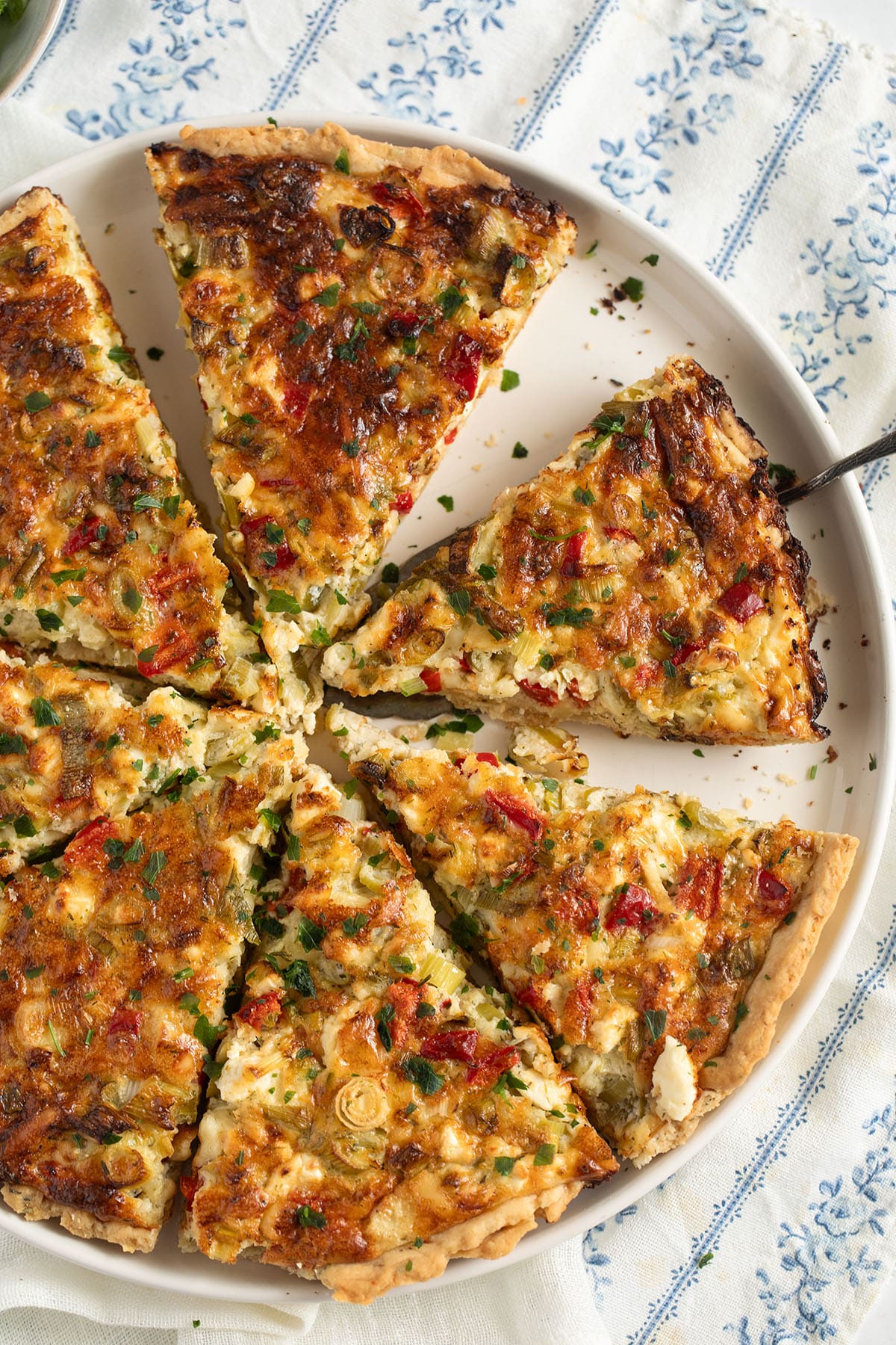 sliced quiche with green onions on a platter.