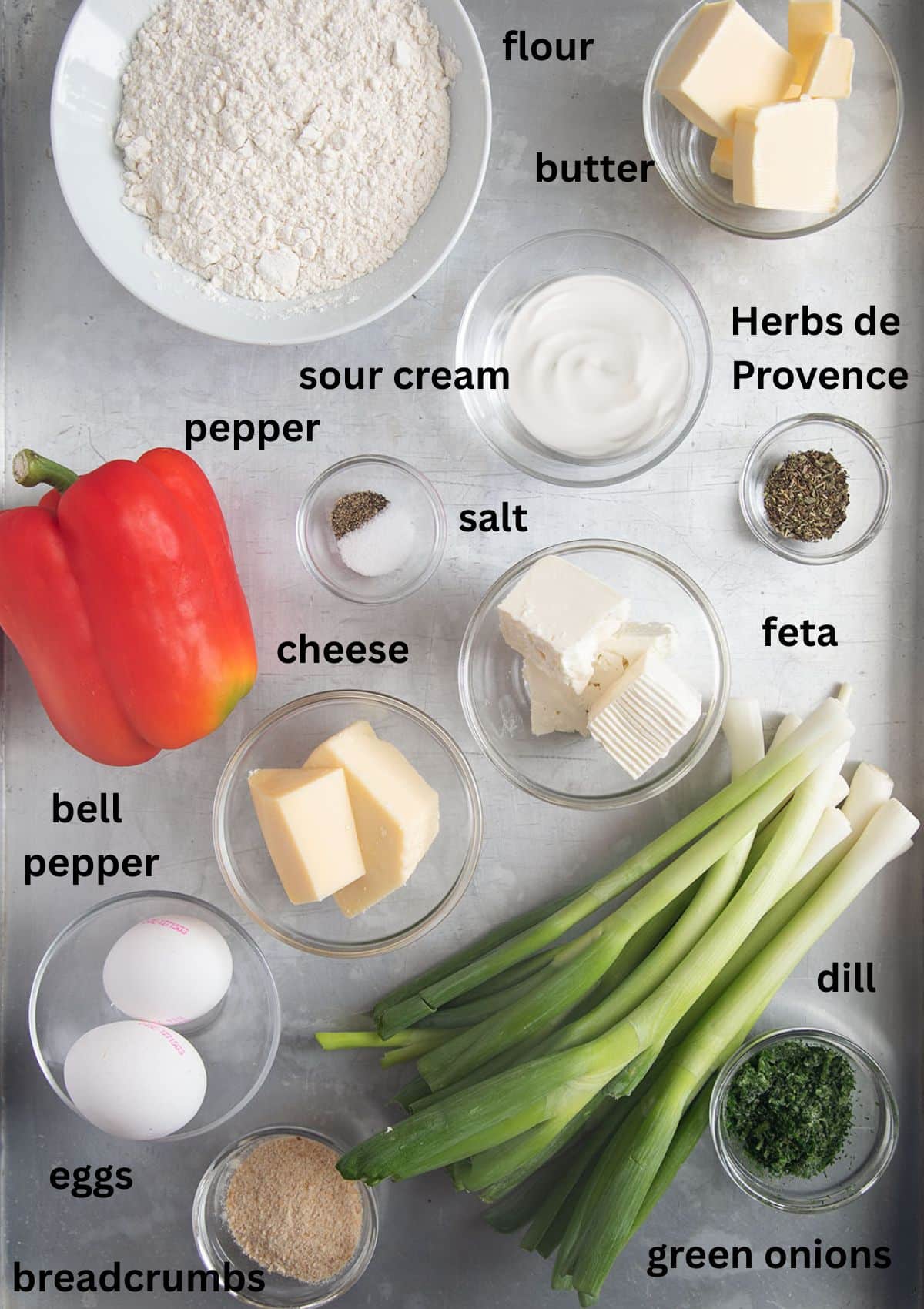 labeled ingredients for making quiche with green onions, pepper, and sour cream on the table.
