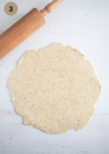 rolled dough for quiche and a rolling pin on the table.