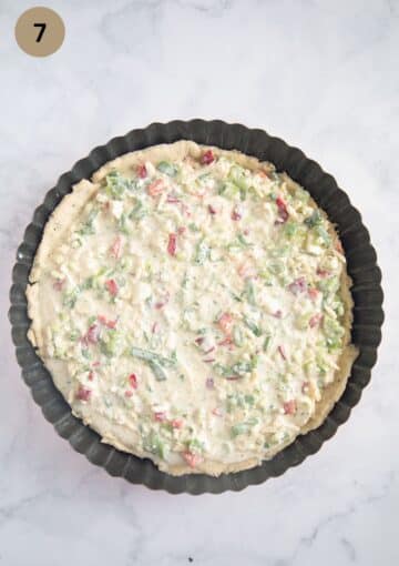 unbaked quiche with green onion and sour cream filling in the baking dish.