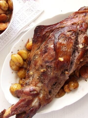 a whole leg of lamb being served on a white platter