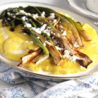 roasted green onions on a platter with polenta and cheese