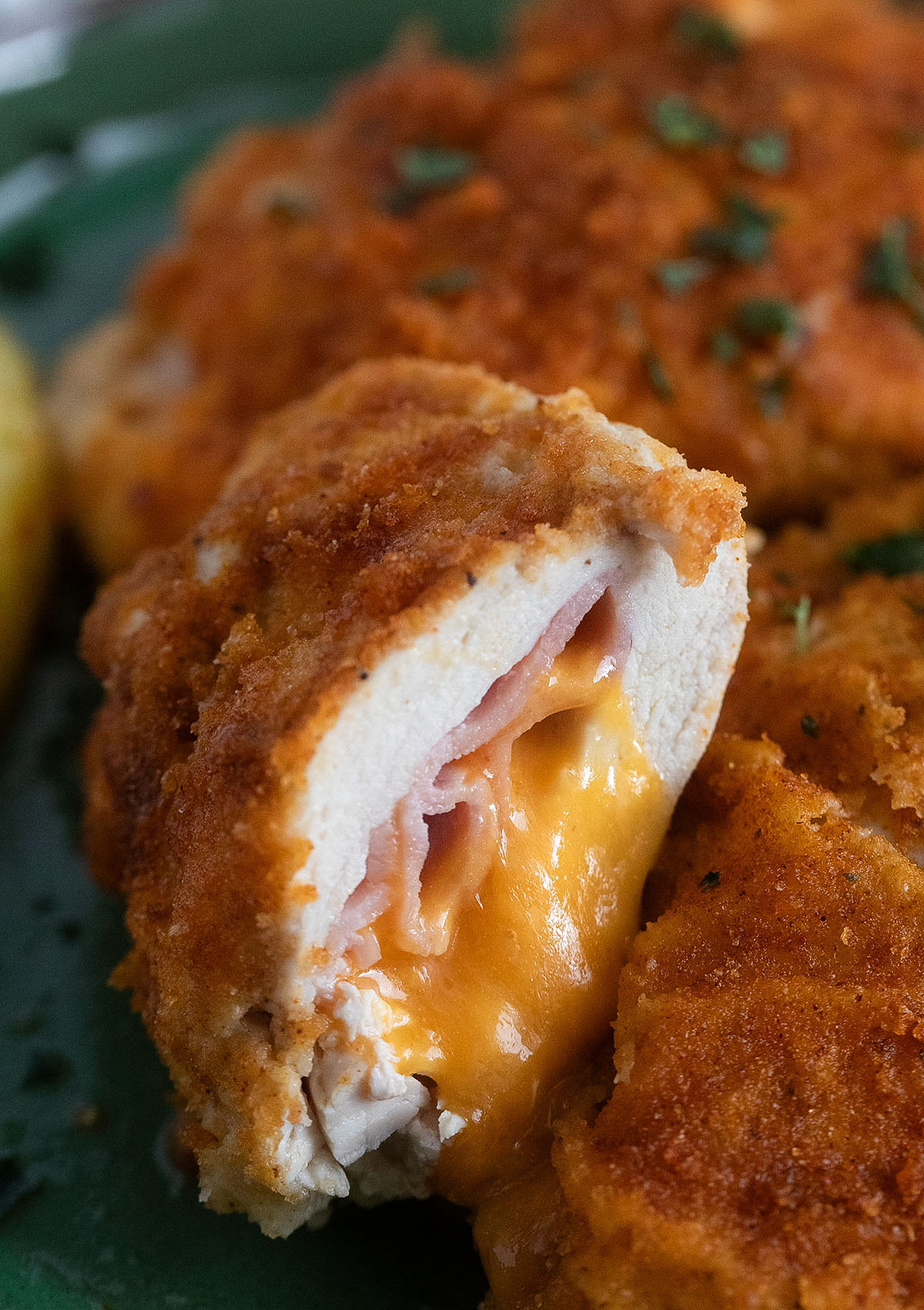 halved cordon bleu chicken schnitzel split to show the ham and the oozy cheese.