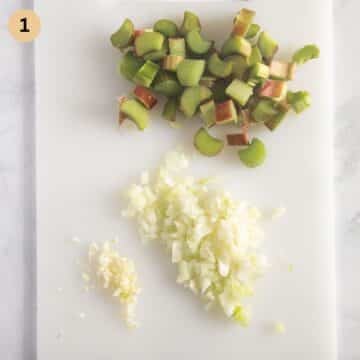 chopped rhubarb, onion, and garlic on a cutting board.