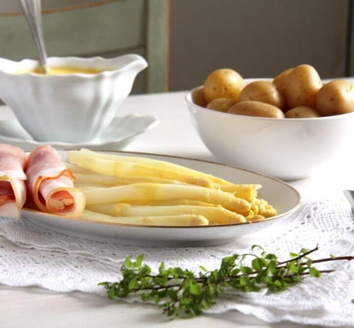 platter with white asparagus, ham, white sauce and potatoes