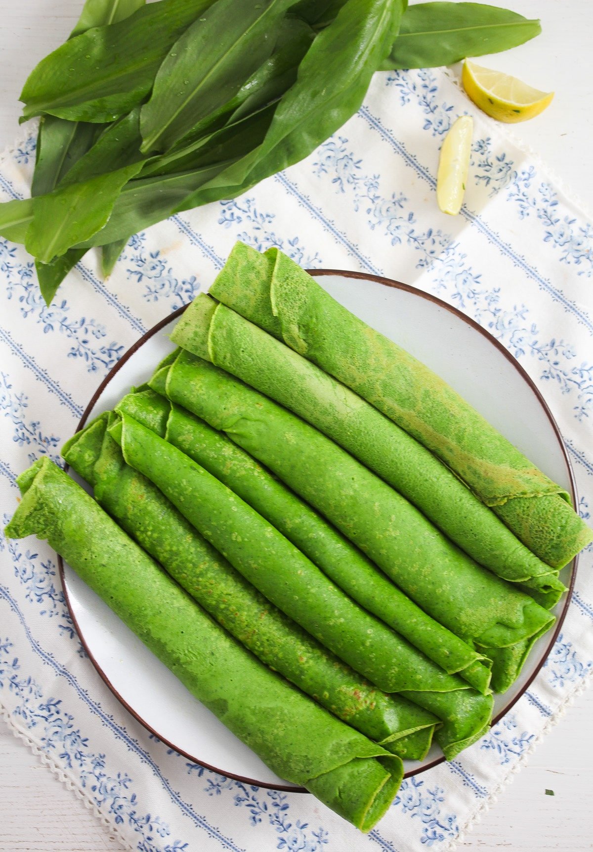 rolled green crepes on a large plate on the table