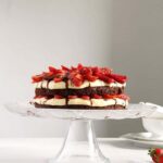 pinterest image of brownie cake with strawberries on a platter.