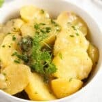 german potato salad with oil and vinegar dressing in a white bowl.