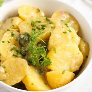 german potato salad with oil and vinegar dressing in a white bowl.