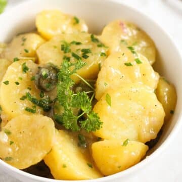german potato salad with oil and vinegar dressing in a white bowl.