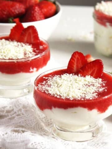 two small dessert glasses with strawberry mascarpone dessert topped with white chocolate.