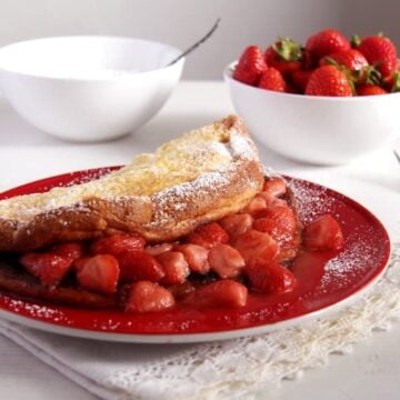 close up strawberry filled thick large pancake on a plate