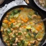 chickpea zucchini curry with coconut milk in a black bowl on the table