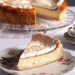 a slice of authentic german cheesecake on a vintage plate, the rest of the cake behind it.