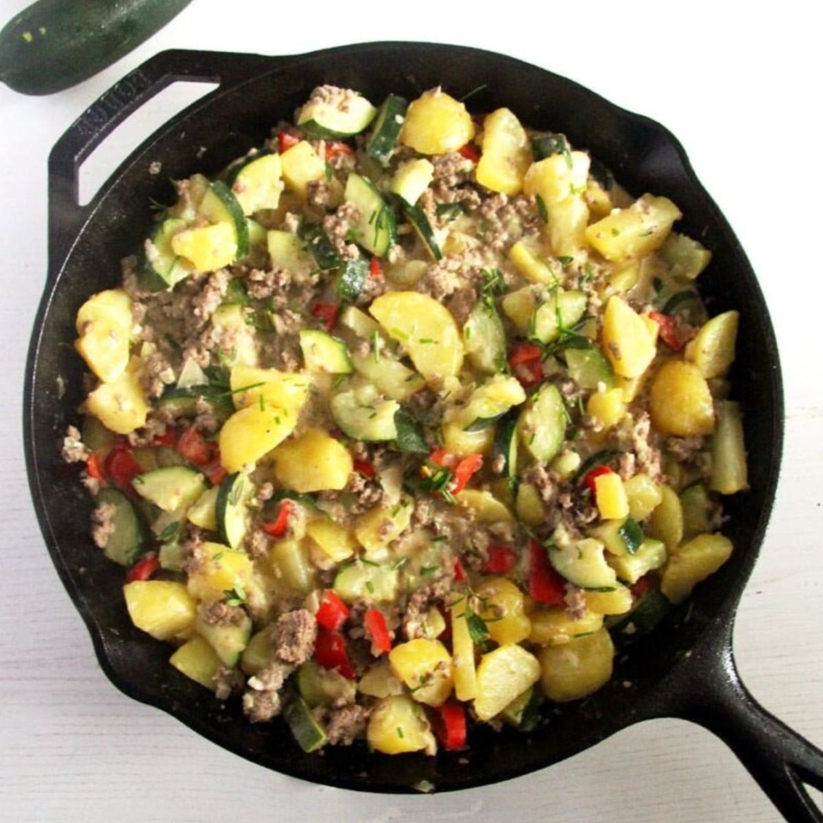 ground beef and zucchini cooked in a large cast iron skillet.
