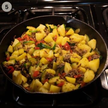 adding cooked chopped potatoes to ground beef and zucchini in a skillet.