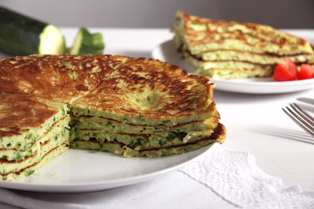 zucchini feta pancakes on a large plate, another plate behind it.