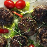 meatballs with zucchini and beef served with cherry tomatoes and salad leaves.