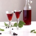 homemade berry drink in a large bottle and two glasses.