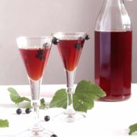 homemade creme de cassis recipe in two small glasses and in a bottle.