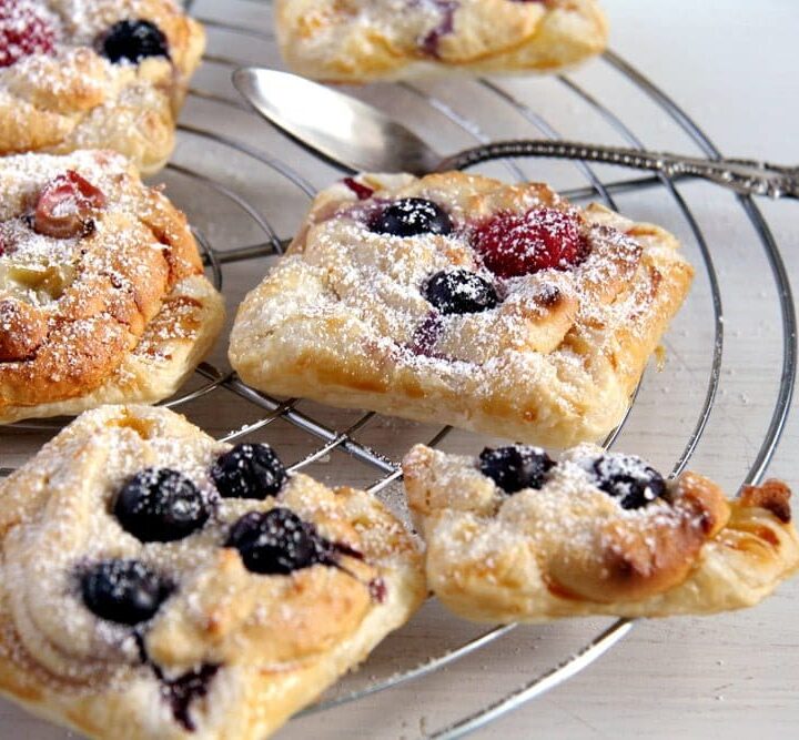 marzipan pastries with puff pastry and berries on a cooling rack