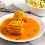two cobs of somali corn in coconut milk sauce sprinkled with parsley.