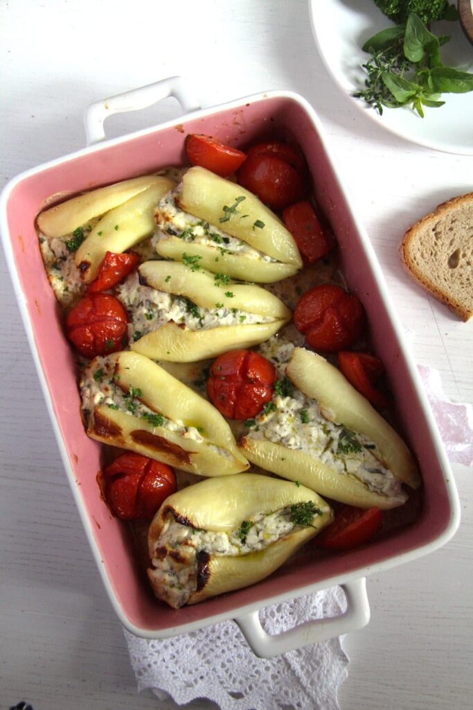 pink baking dish with feta stuffed peppers and small tomatoes