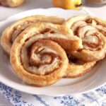 apple puff pastry rolls with cinnamon on a small white plate