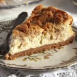 a slice of creamy apple streusel cheesecake on a small plate.