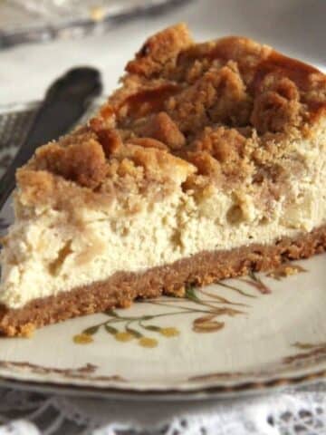 a slice of creamy apple streusel cheesecake on a small plate.