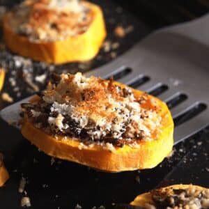 roasted butternut squash slice being lifted from the tray.