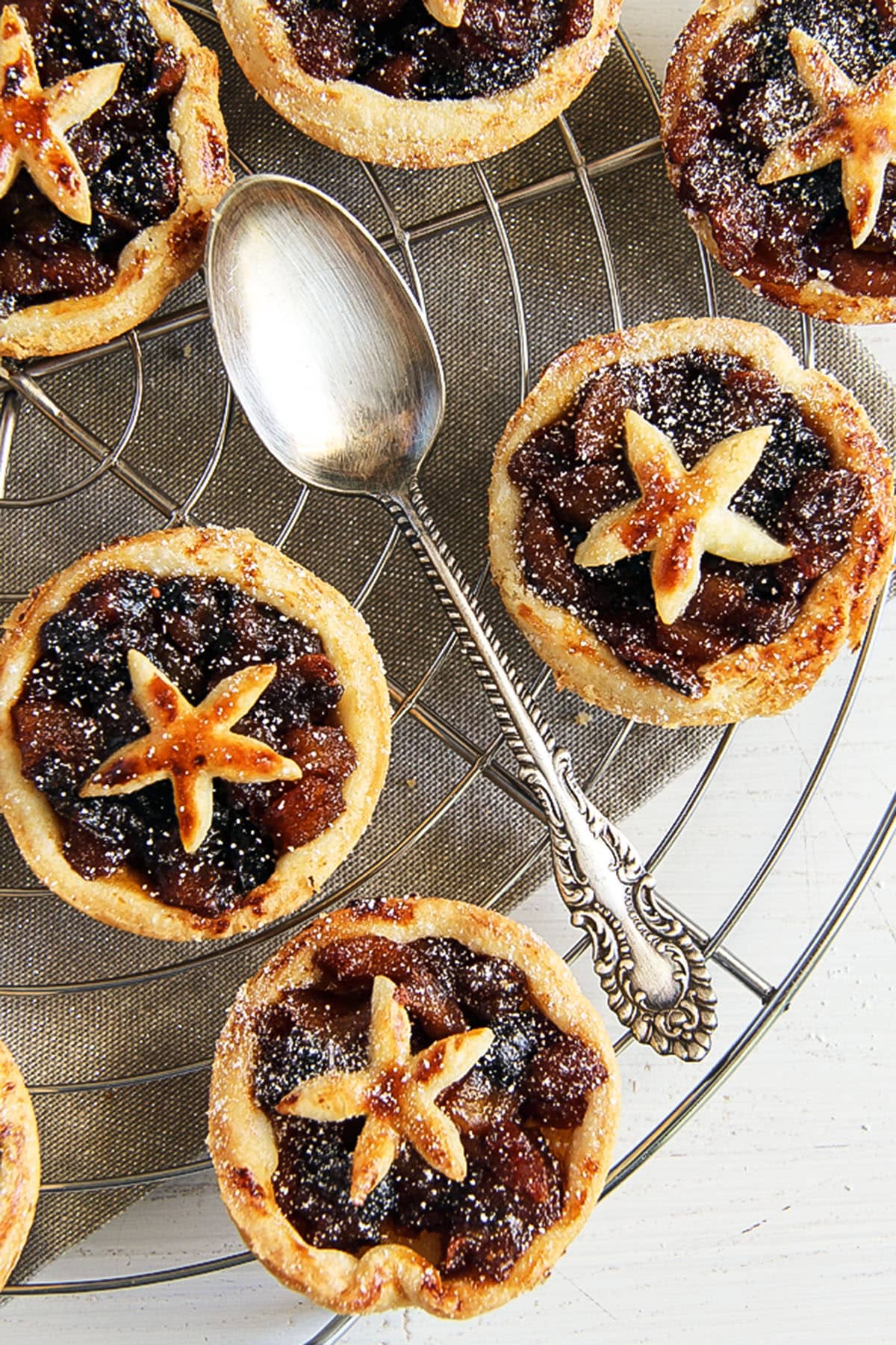 several small mincemeat pies and a spoon on a wire rack.