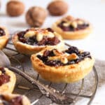 mincemeat tarts with homemade filling on a wire rack, walnuts behind it.