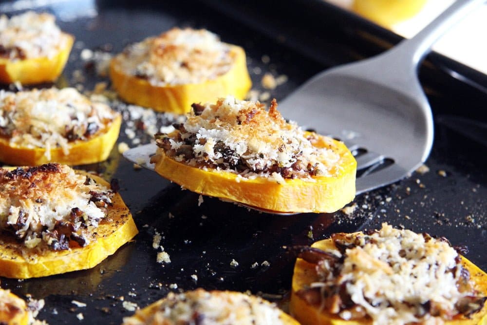 roasted squash slices with parmesan on a black baking tray