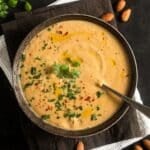 creamy and vegan cauliflower almond soup in a bowl with a spoon in it.
