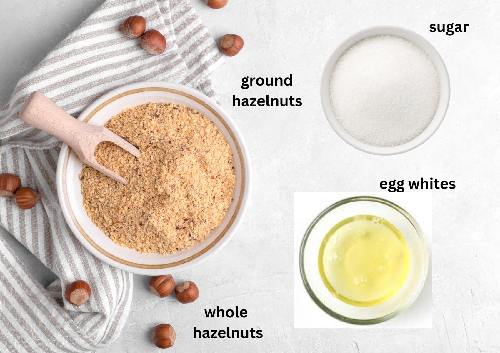 ground hazelnuts, sugar and egg whites in bowls, all labeled ingredients for macaroons.