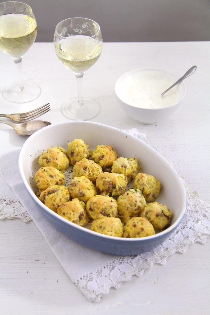cornmeal balls with sausages and cheese in a blue baking dish