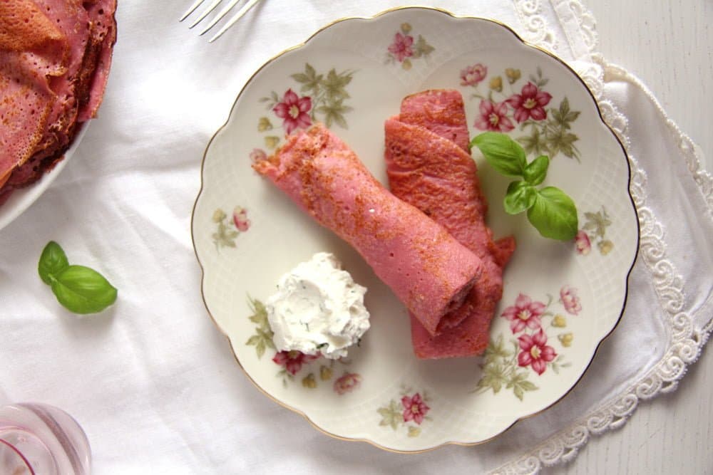 two rolled pink crepes ona vintage plate with dip and basil.